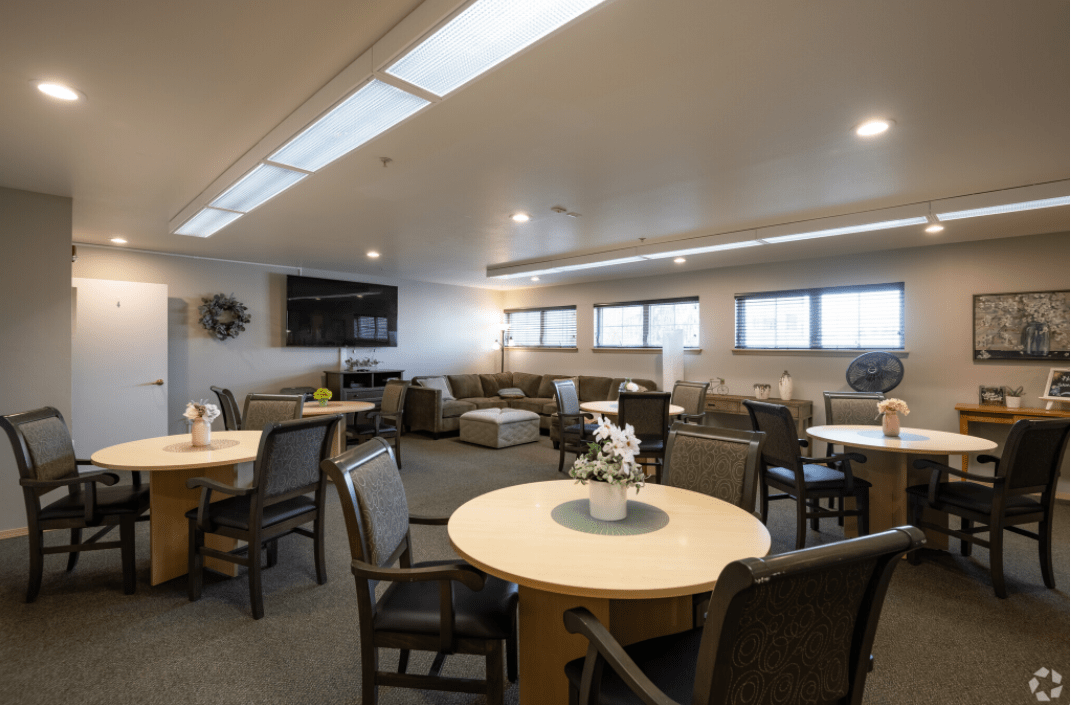 A modern lounge area with tables, chairs, and a television.