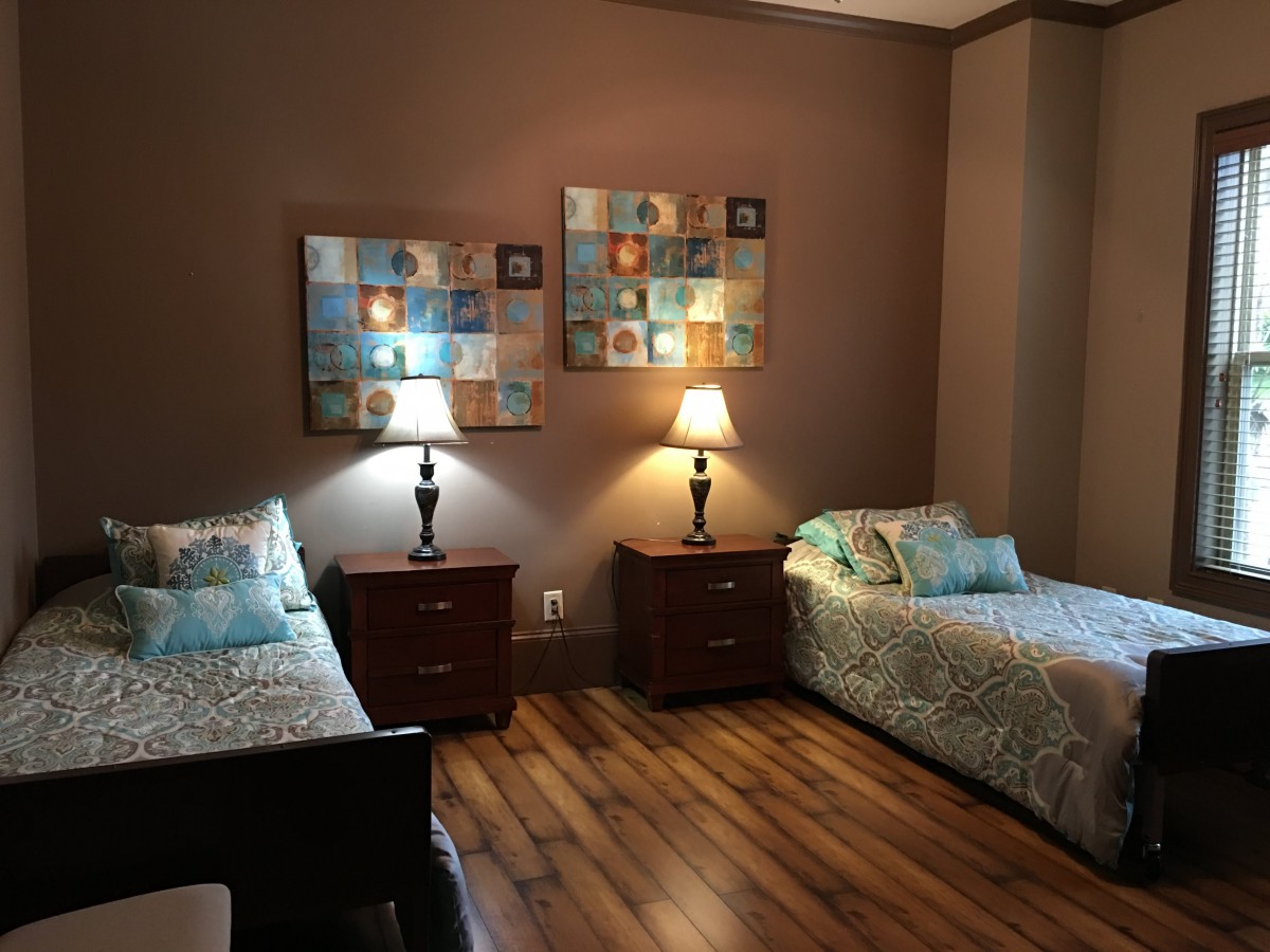 A cozy bedroom with twin beds, elegant nightstands, and warm lighting.
