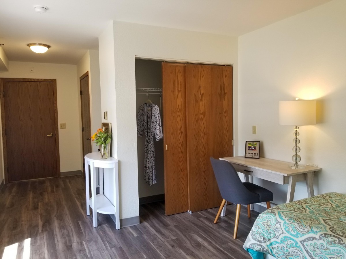 A cozy bedroom with a desk and chair, wooden closet doors, and modern decor.