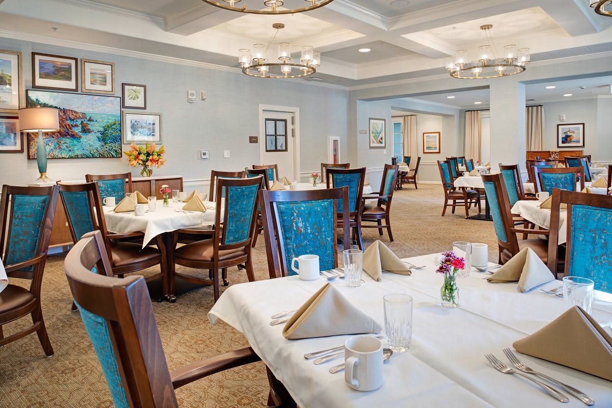 An elegantly furnished dining room with neatly arranged tables and decorative lighting.