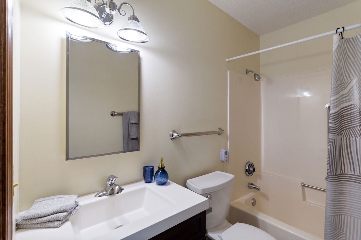 A modern bathroom with a sink, mirror, toilet, and shower.