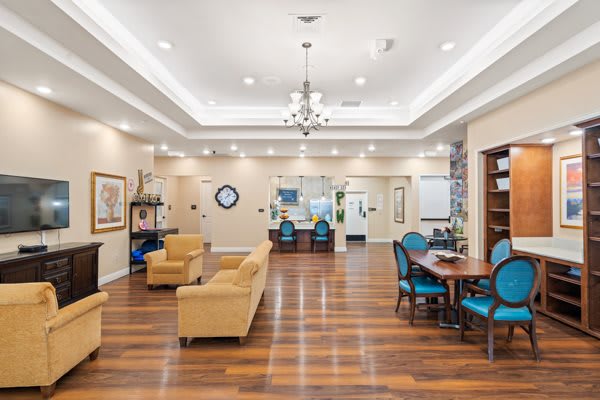 A spacious and elegantly designed lounge area with comfortable seating, hardwood floors, and a chandelier.