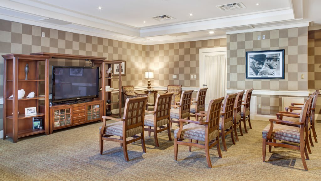 A neatly arranged conference room with wooden chairs facing a television.