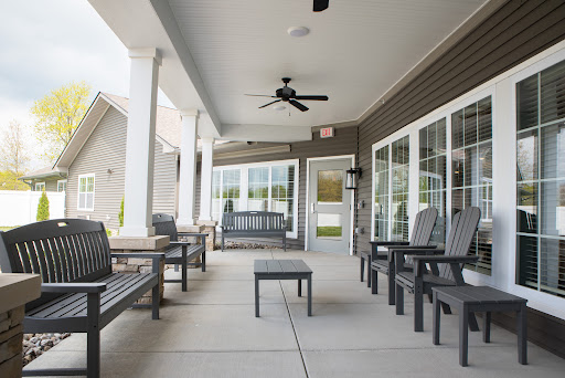 A serene outdoor patio featuring comfortable seating and a ceiling fan, ideal for relaxation.