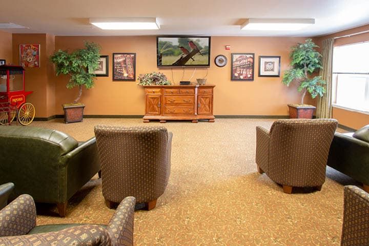 A cozy lounge area with comfortable chairs, a television, and decorative artwork on the walls.