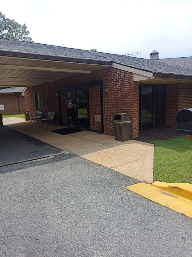 A view of a brick building entrance with a covered area and parking space.