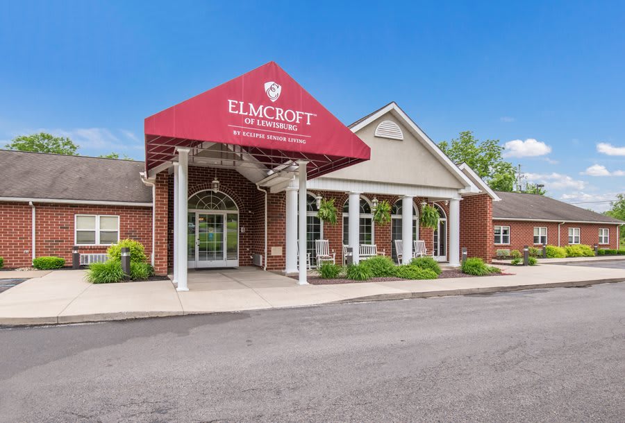 Front view of a commercial building with a red awning and well-maintained landscaping.