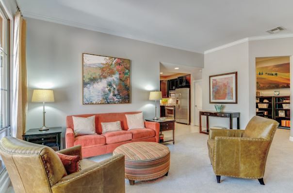 A cozy living room with a warm color palette, featuring a coral sofa, abstract artwork, and ambient lighting.