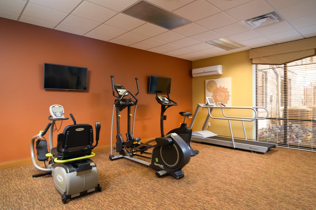 A gym room with exercise equipment including a treadmill and stationary bike.