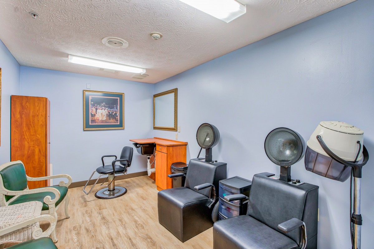 A beauty salon interior with hair drying chairs and a styling station.