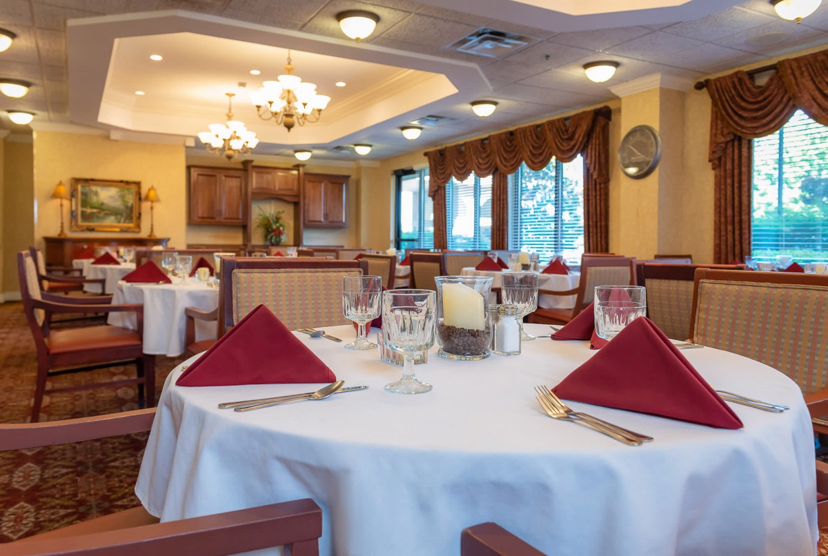 An elegant dining room with neatly set tables and red napkins.