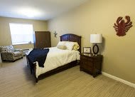 A cozy bedroom with a neatly made bed, nightstand, and lamp.