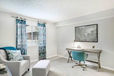 A bright and airy home office with a minimalist design featuring a desk, chair, and large map artwork.