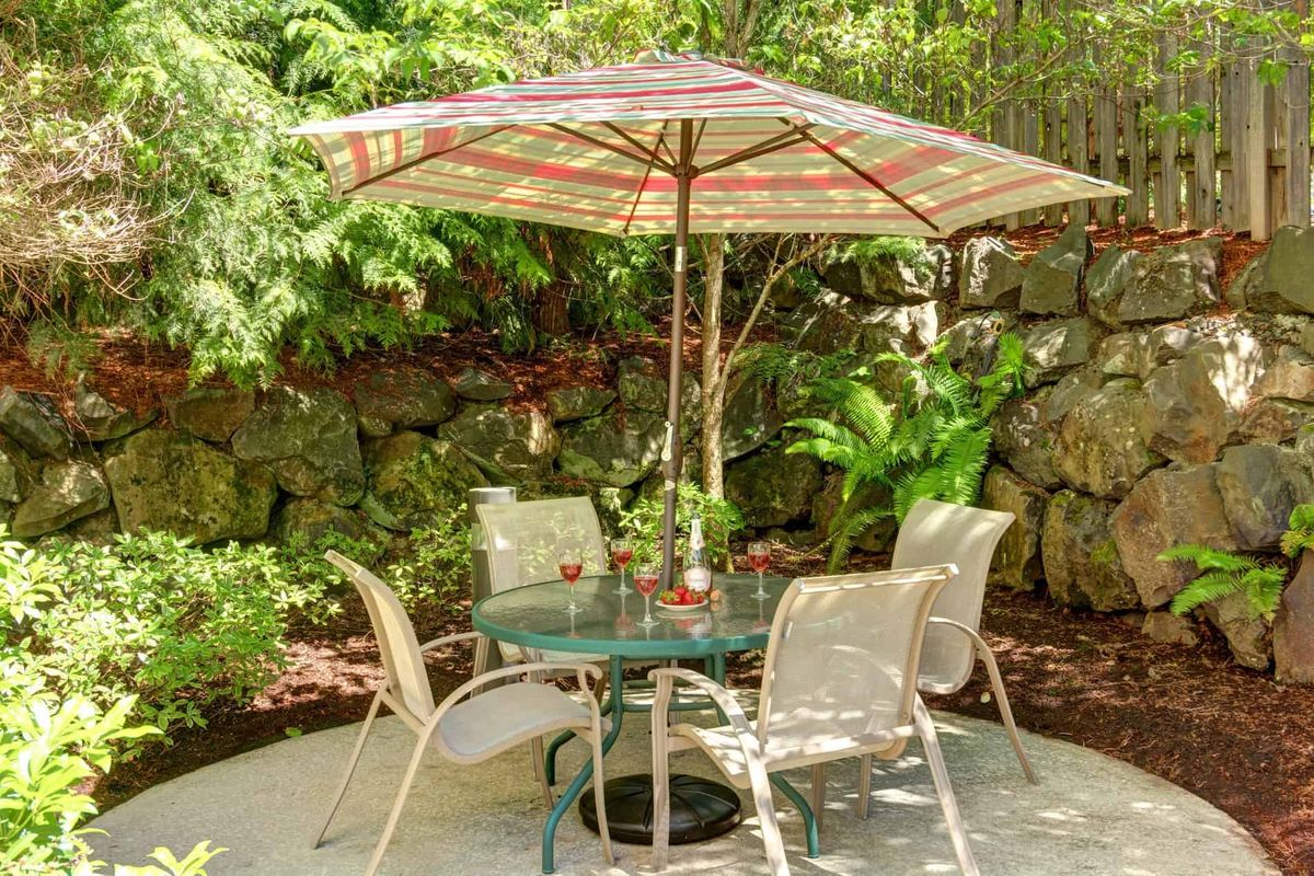 Outdoor patio set with table, chairs, and umbrella in a garden setting.