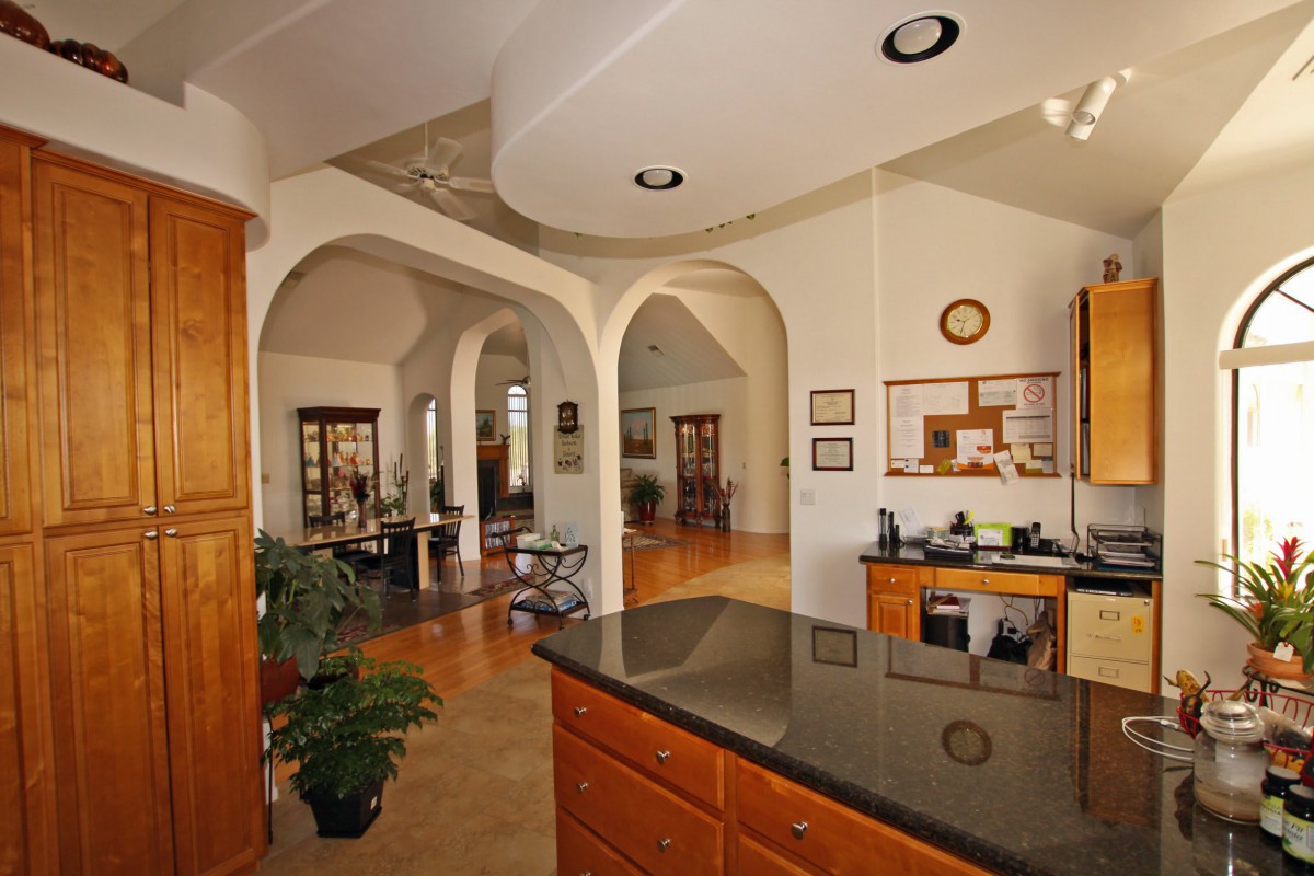 A modern open-concept living space featuring arched doorways and warm hardwood floors.