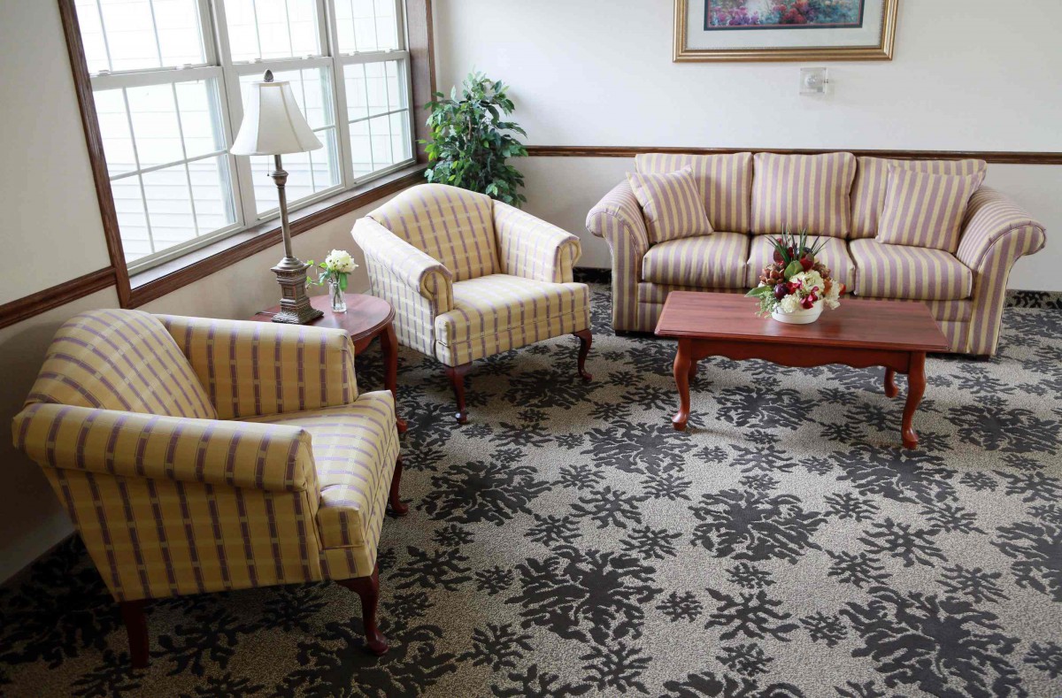 A cozy living room with a sofa, armchairs, and a coffee table on a floral-patterned carpet.