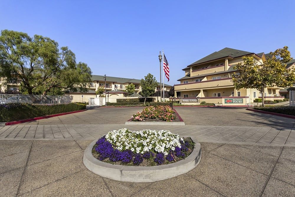 A well-maintained courtyard with flowers and a flagpole in front of a building.