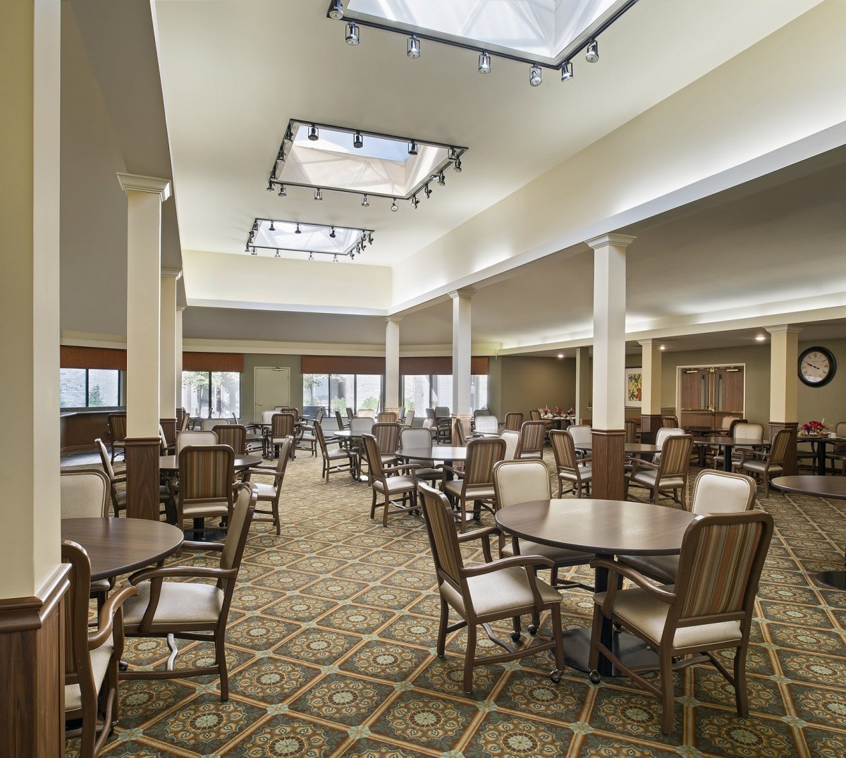 A spacious dining hall with multiple tables and chairs, well-lit and carpeted.