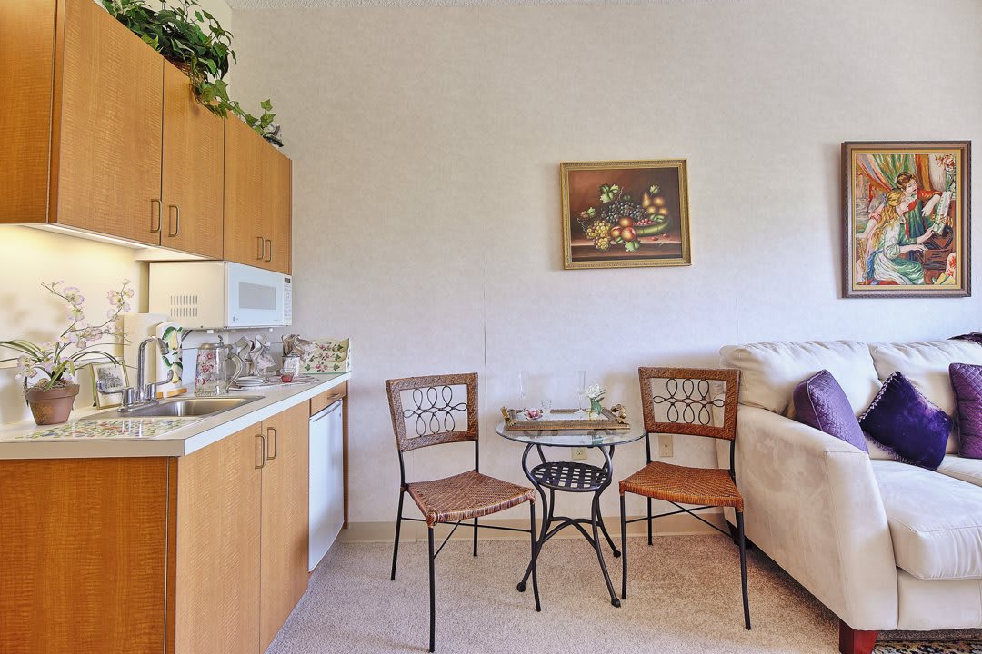 A small kitchen area with a table, chairs, and a sofa.