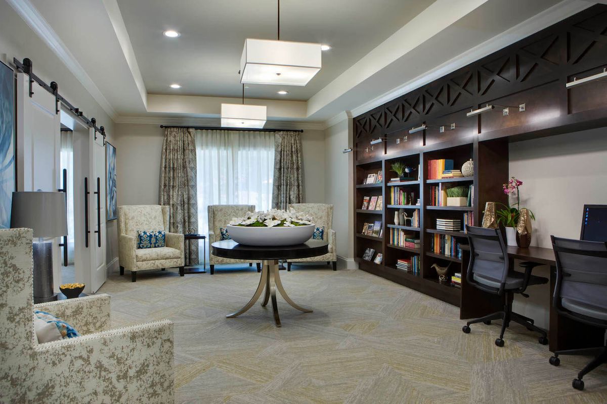 A modern, cozy library room with bookshelves, comfortable seating, and elegant lighting.