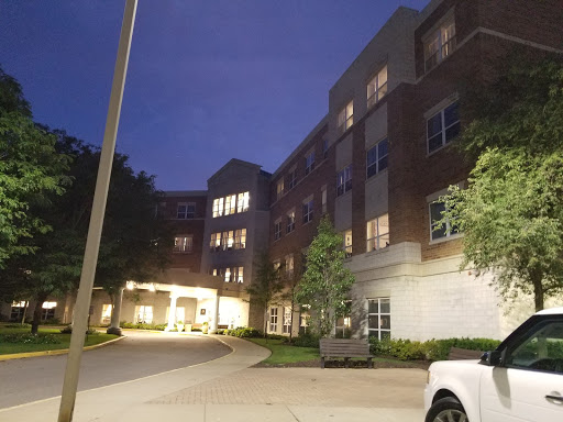 A quiet evening view of a residential building, illuminated against the night sky.