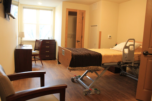 A well-lit hospital room featuring a bed, desk, and comfortable seating.