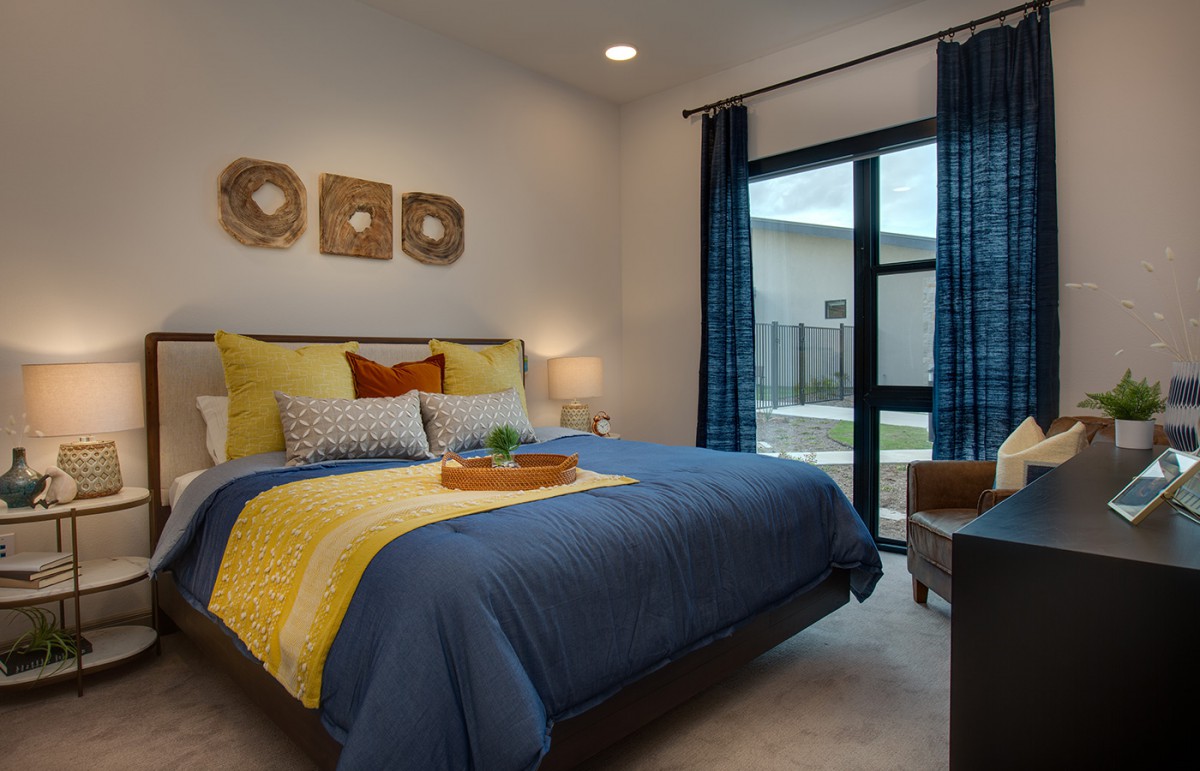 A modern and cozy bedroom with colorful bedding and natural light.