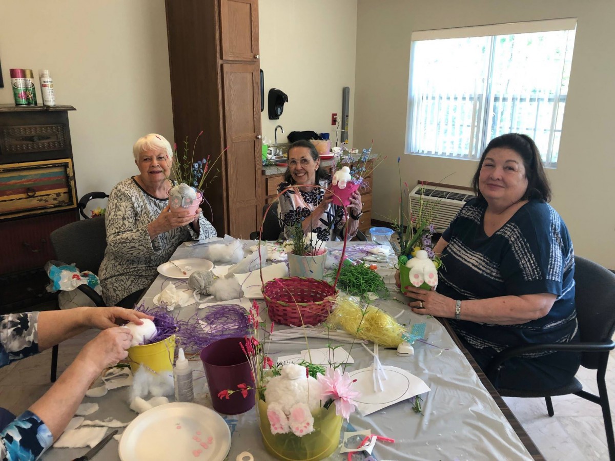 A group of women enjoying a crafting session with flowers at a table indoors.