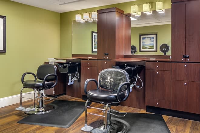 A modern hair salon interior with two styling chairs and mirrors.