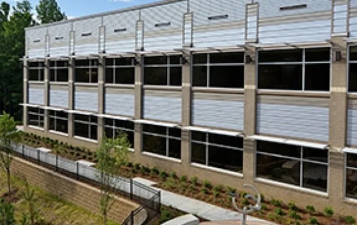 A modern building exterior with multiple windows and a landscaped area.