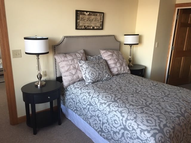 A cozy bedroom with a neatly made bed, flanked by nightstands and lamps.