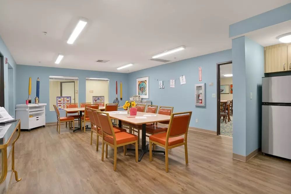 A modern dining room with blue walls and orange chairs surrounding a table decorated with flowers.