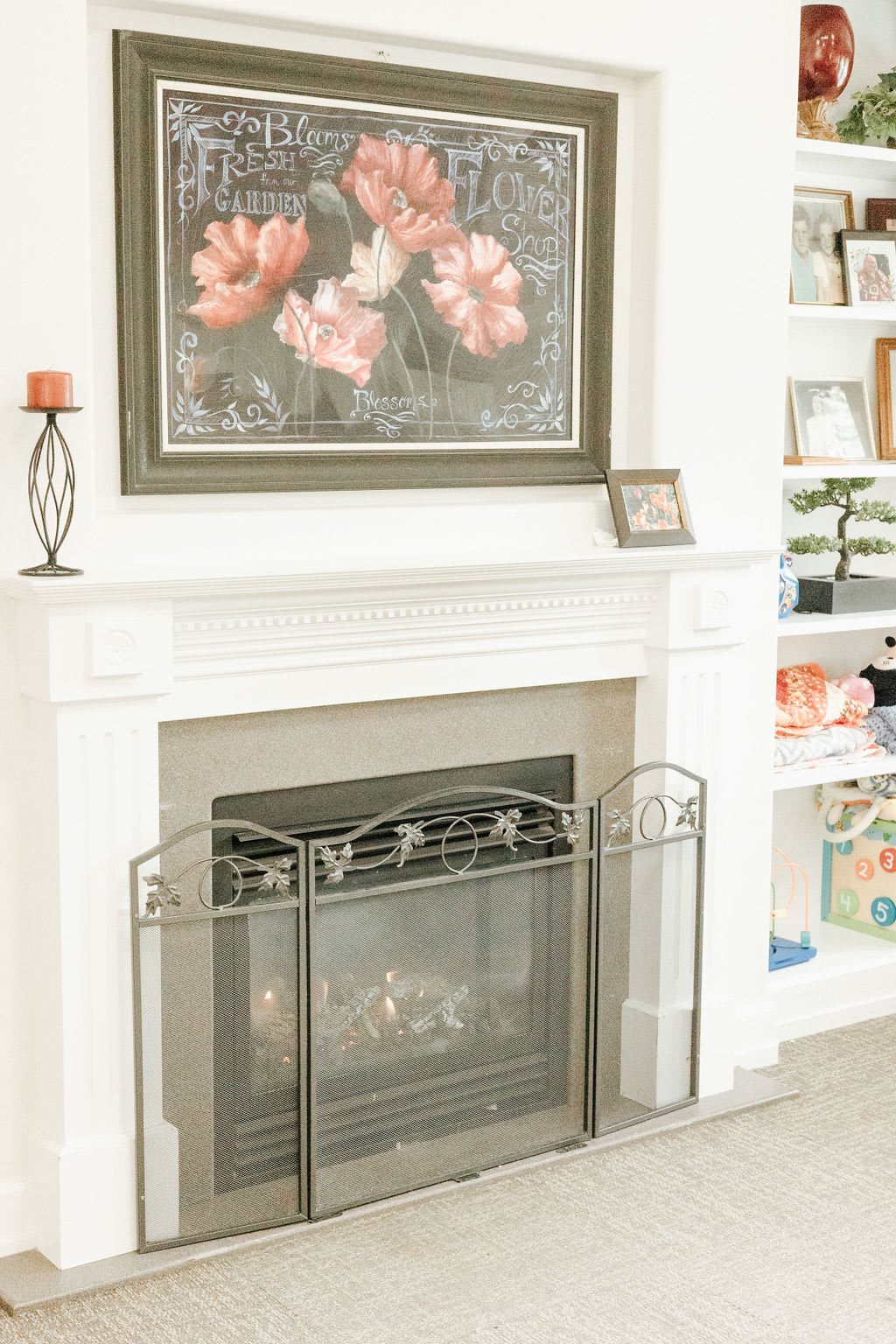 A cozy living room with a white fireplace adorned with floral artwork and decorative shelves.