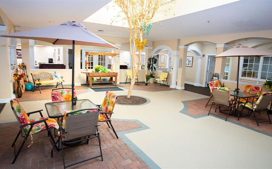 A bright indoor seating area with tables, chairs, and plants under a skylight.