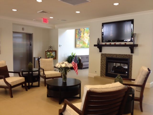 A cozy waiting area with comfortable seating, a television mounted above a fireplace, and tasteful decorations.