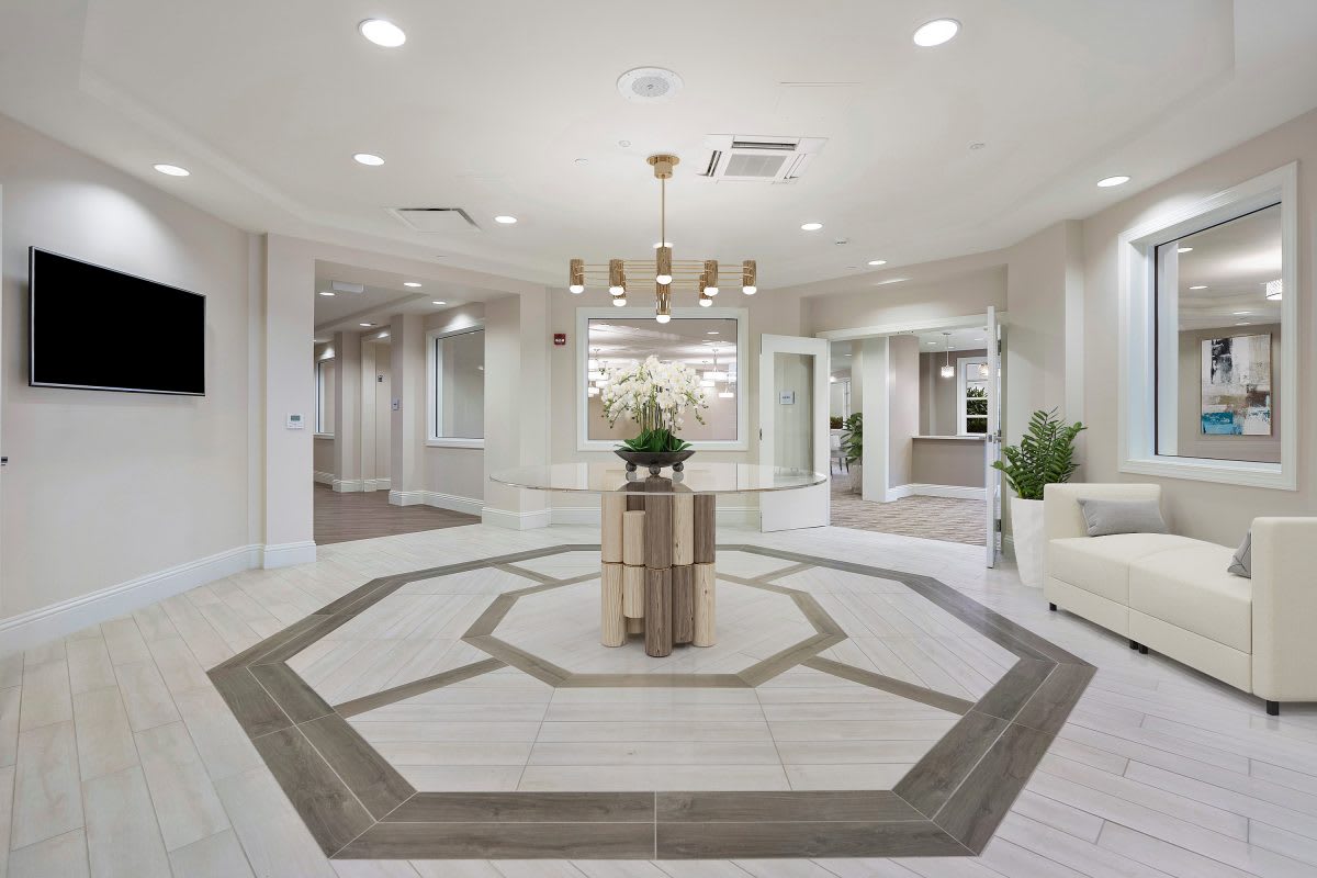 A modern and elegantly designed lobby with a central table and chandelier.