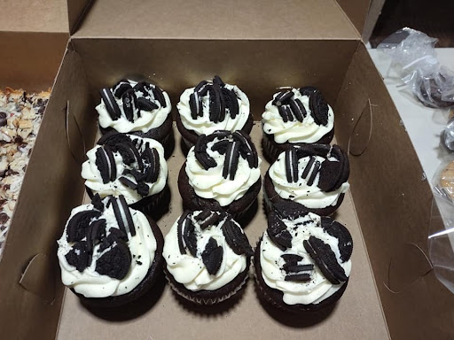 A delightful box of Oreo-themed cupcakes, topped with creamy frosting and cookie pieces.