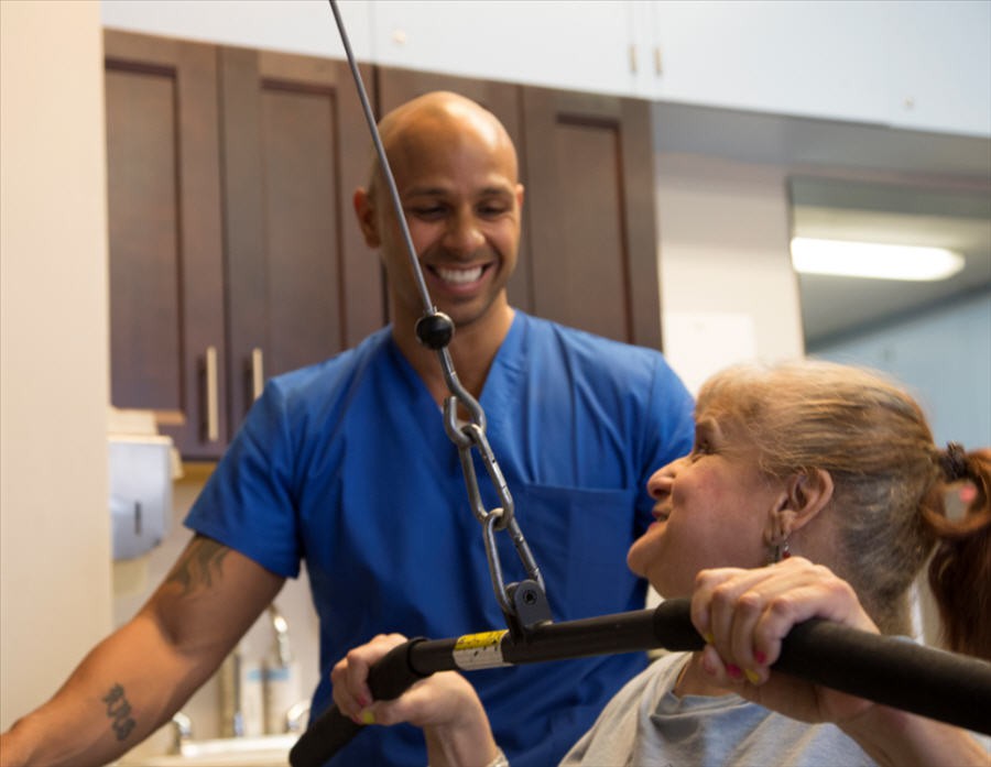 A therapist assisting a patient with physical exercises in a healthcare setting.