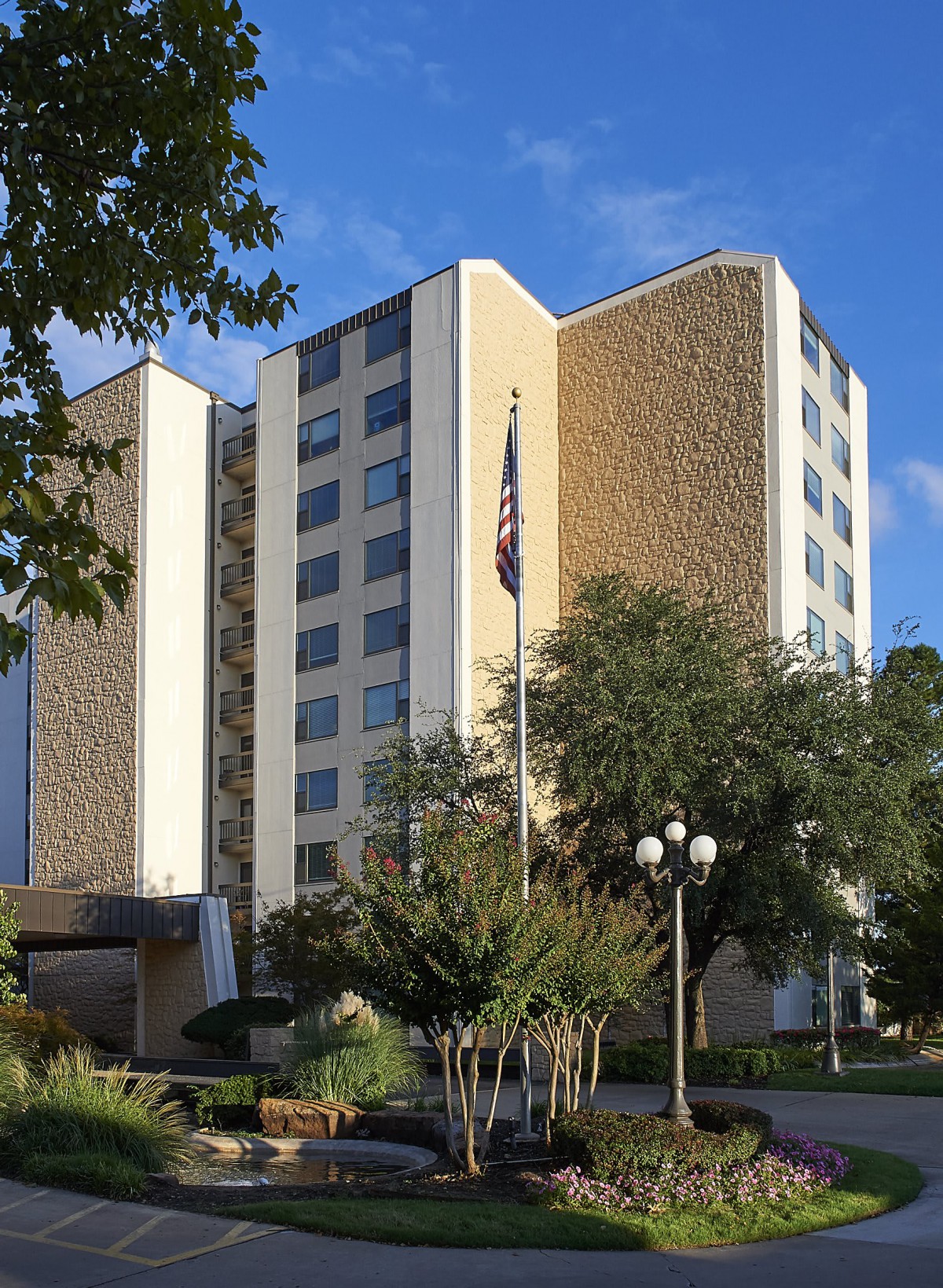 A modern multi-story building with trees and an American flag in front.
