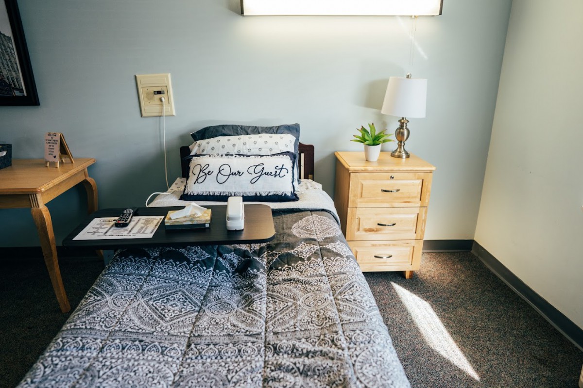 A cozy bedroom with a bed, nightstand, and decorative pillows.
