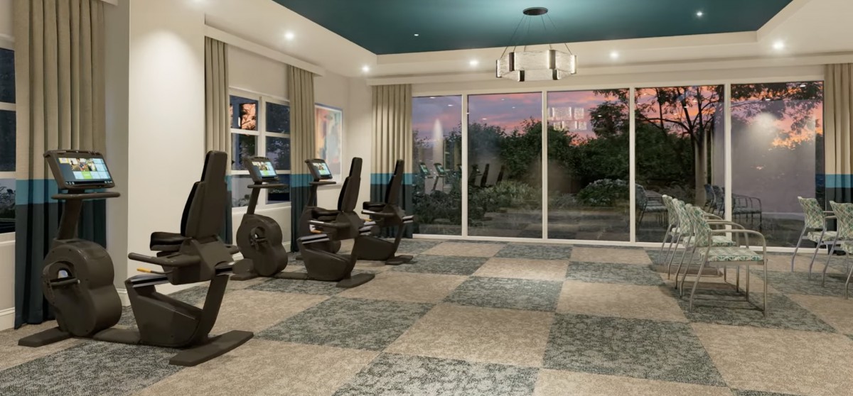 A modern gym room with exercise equipment and large windows overlooking a scenic view.