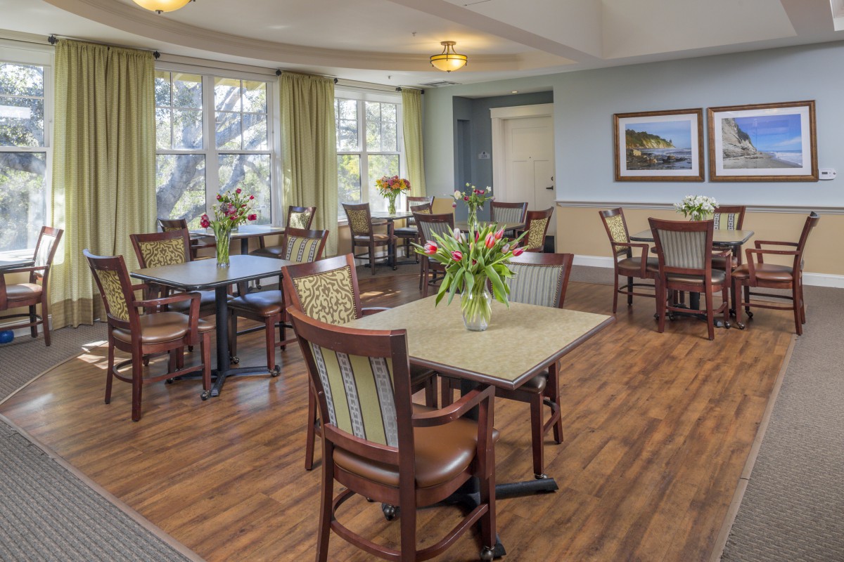 A bright, inviting dining room with wooden floors and well-arranged tables and chairs.