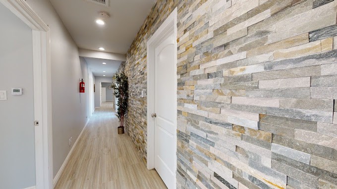 A modern hallway with stone walls, wood flooring, and a white door.