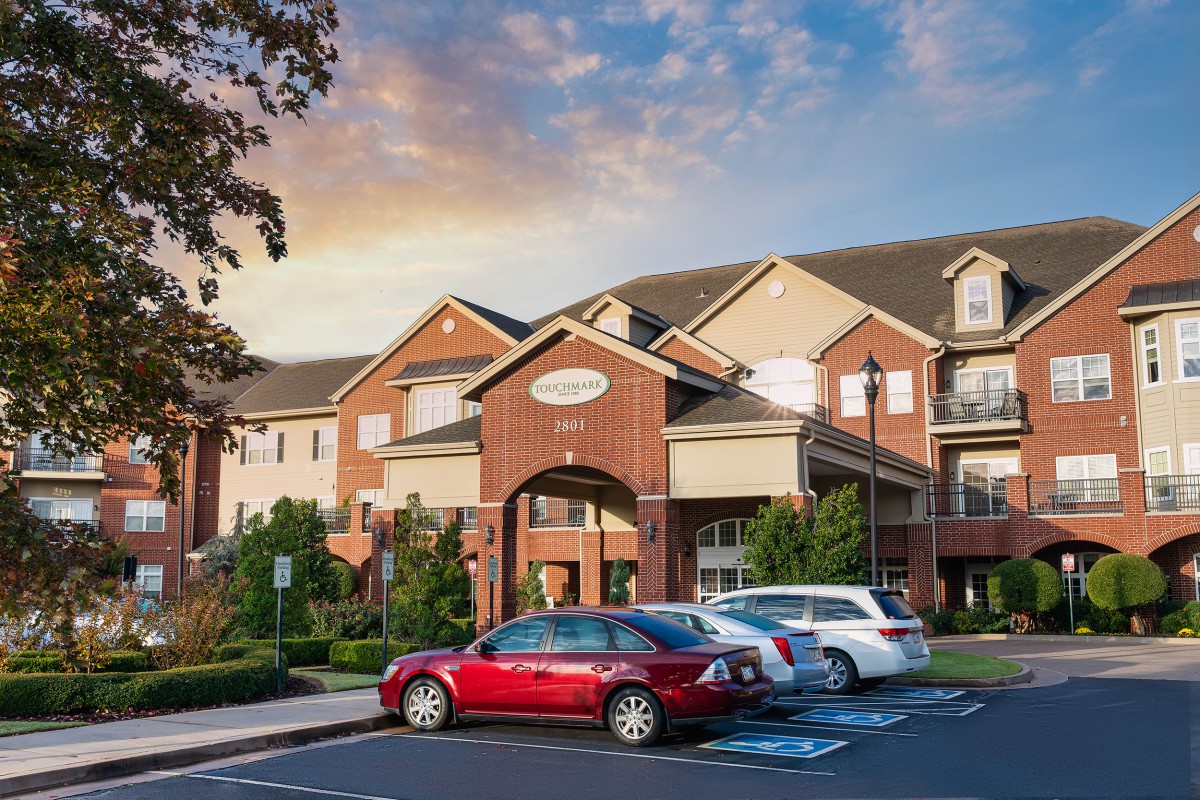 A suburban residential building with a parking lot at sunset.