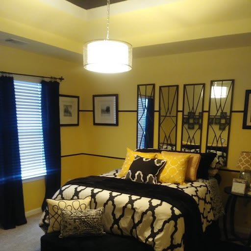 A modern bedroom with yellow walls, black and white bedding, and decorative mirrors.