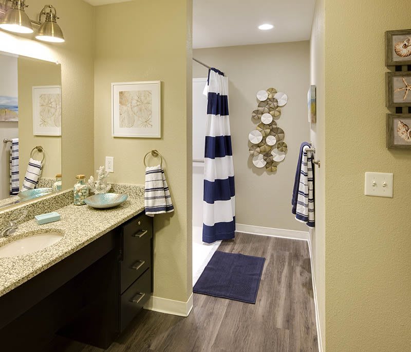 A modern bathroom featuring a large mirror, sink, striped shower curtain, and decorative elements.
