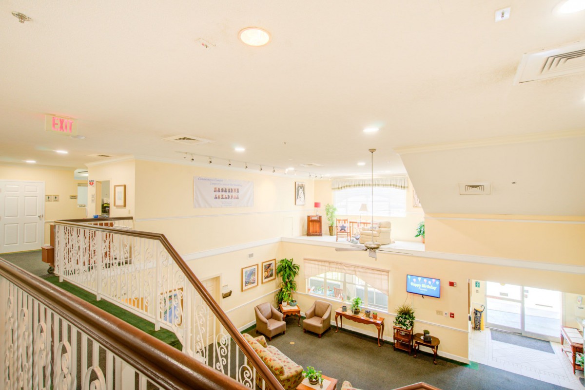 A bright, welcoming interior space featuring a staircase, comfortable seating, and decorative elements.