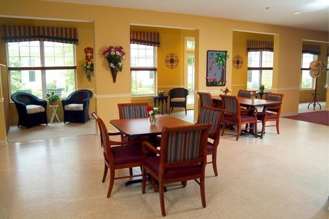 A cozy dining area with wooden tables and chairs, yellow walls, and natural light coming through the windows.