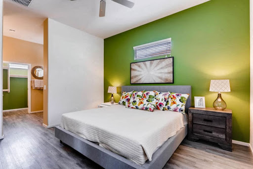 A cozy modern bedroom featuring a vibrant green accent wall, floral patterned pillows, and stylish nightstands.