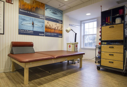 A well-organized physiotherapy room featuring a treatment bed and various therapeutic equipment.
